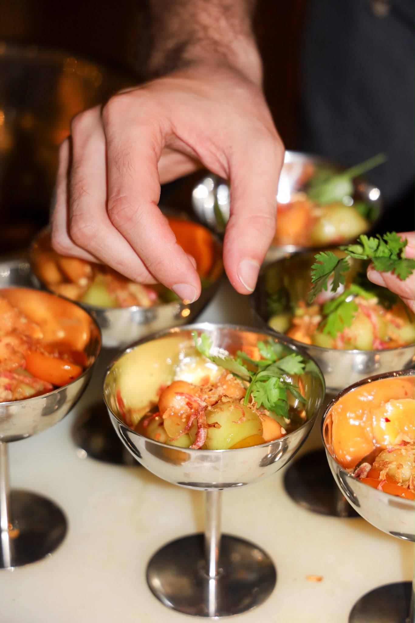 A colorful vegetable course being finished by hand during service