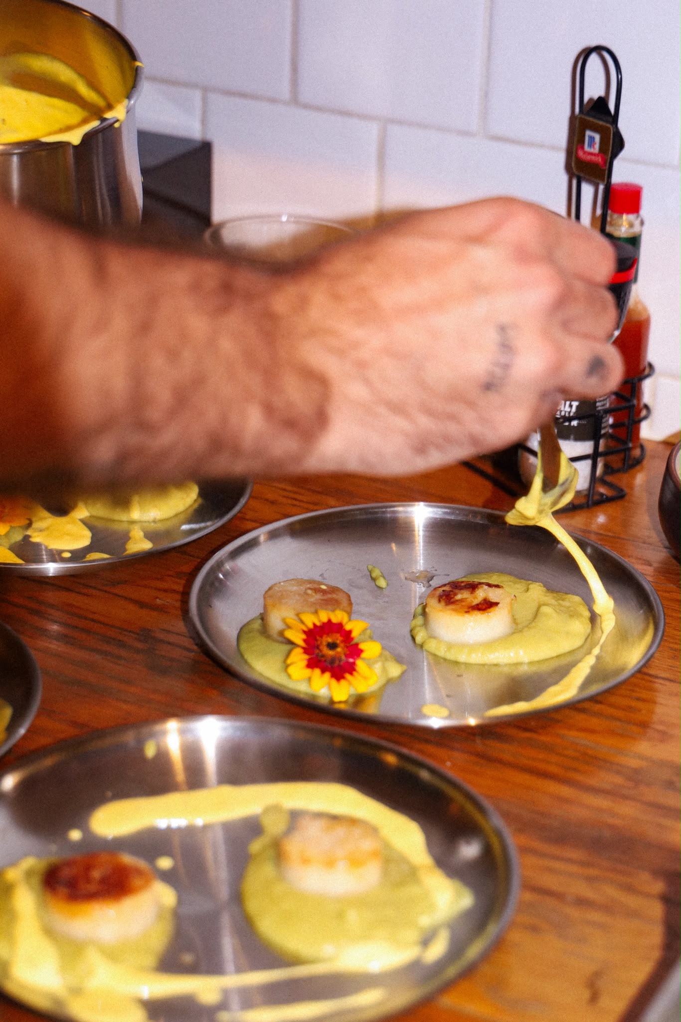 Scallops plated with yellow sauce and edible flowers