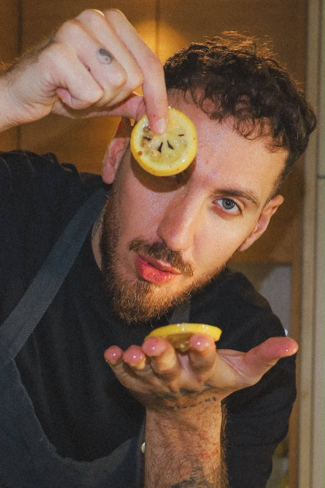 Giuseppe Costanzo playfully holding fresh lemon slices in his kitchen