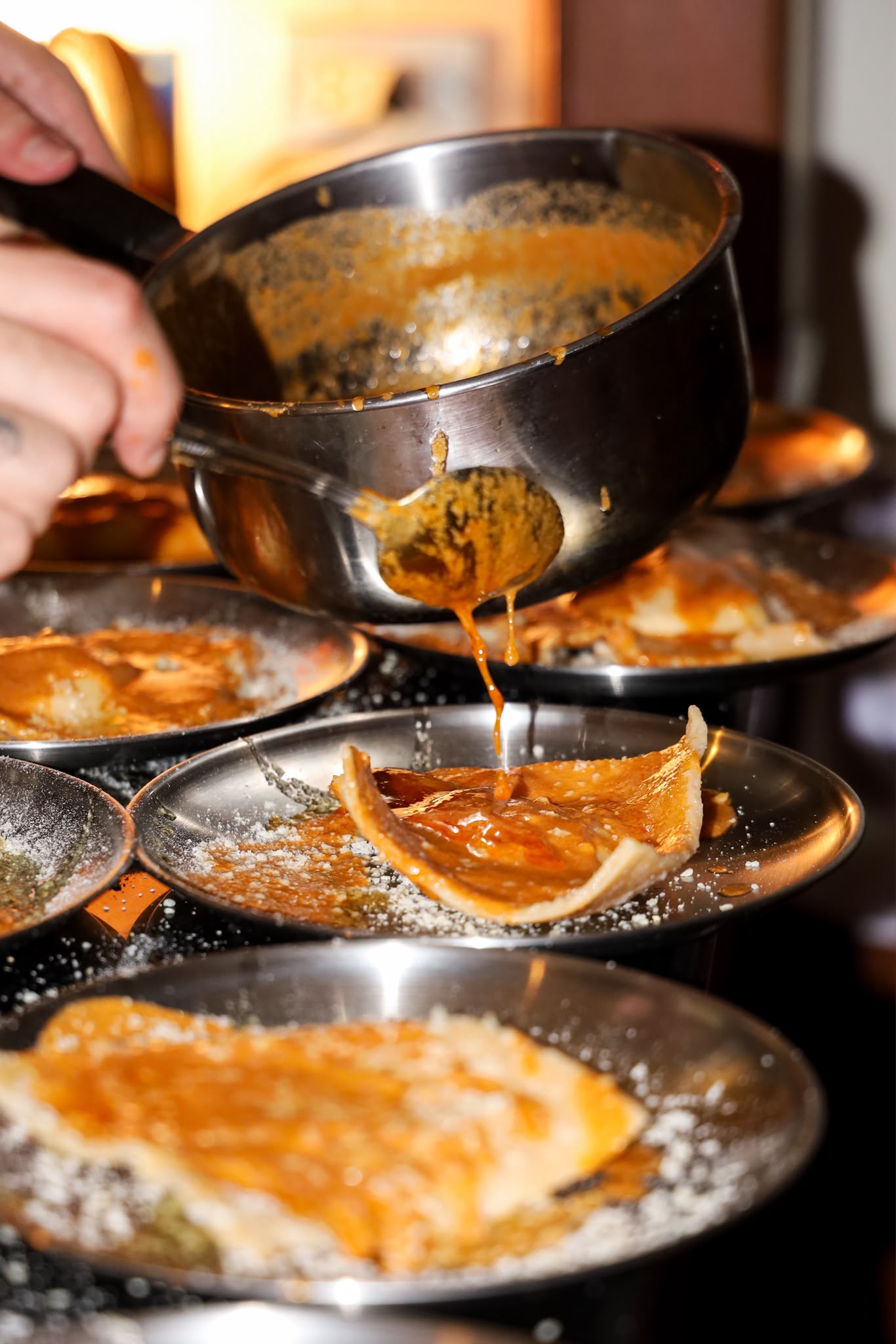 A warm sauce being spooned over plated bread during service