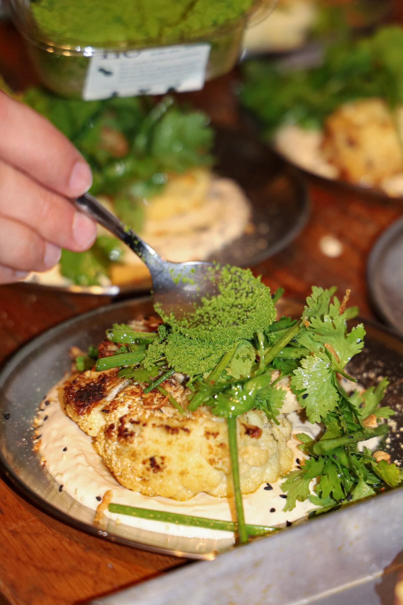 Grilled cauliflower with herbs and green seasoning being finished at the pass